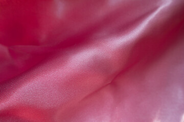 Diagonal fold on pink satin polyester fabric