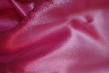 Smooth pink satin polyester fabric in soft folds