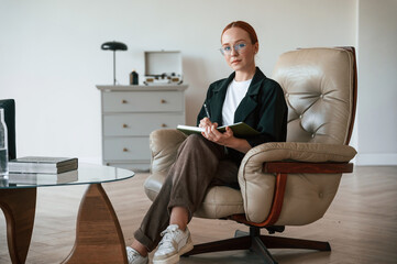 Woman psychologist in formal clothes is with notepad indoors