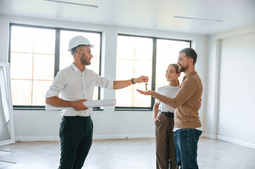 Obraz premium Happy new owners, taking keys. Realtor shows an apartment to a young couple