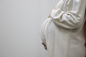 pregnant Arabic muslim female on isolated white background touching her tummy showing her body shape during 9th month of pregnancy