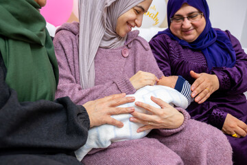 mother and mother in law celebrating new born baby holding gifts and rounded with balloon