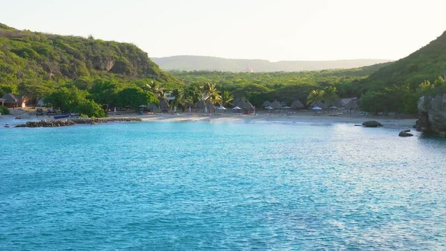 Aerial rising establishes lush tropical valley with gorgeous sandy beach in Caribbean