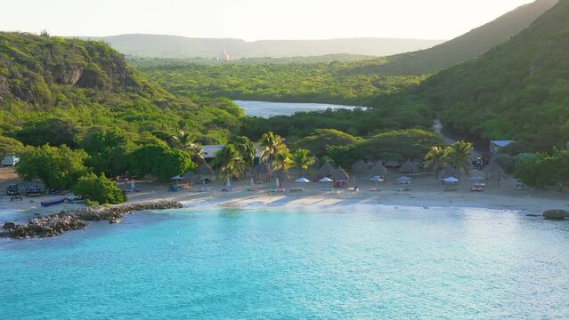 Slow aerial pan across turquoise blue water and palm trees of Daaibooi beach curacao