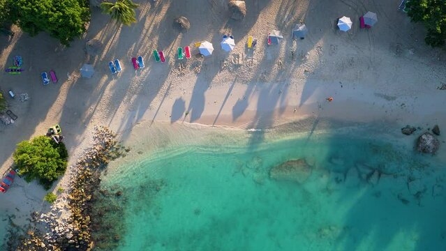 Top down descending view of ocean waves crashing on beach of Curacao, solo person walks on sand