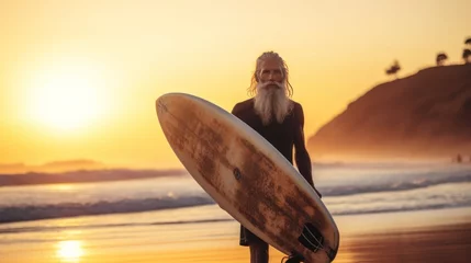 Tuinposter Portrait of senior man with surfboard on the beach at sunset. Sport concept. Vacation and Travel Concept with Copy Space. © John Martin