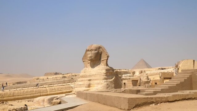 Pan down to reveal an Egyptian sphinx with the Pyramids of Giza in the background. Short travel video in Egypt.