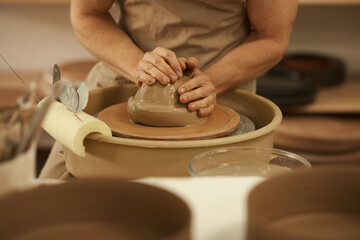 Ceramist turning a piece of clay on a wheel in a studio