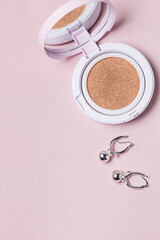 Powder Cushion for makeup and earrings on a Pink Background Makeup Products and Bijouterie Vertical Background Copy Space