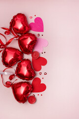 St Valentine's Day concept Top view photo of heart shaped shiny red balloons and confetti on pastel pink background