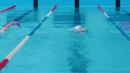 Young man and woman swimming freestyle in a swimming pool at a relaxed pace. Taking care of your health, enjoying swimming. Athletes train in freestyle swimming, fitness and body care.