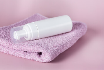 White cosmetics container mockup with towels on Pink background Horizontal Copy Space