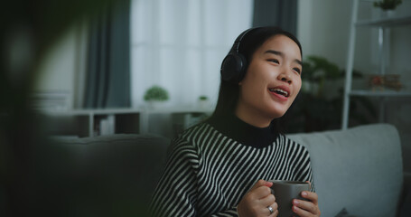 Portrait of Happy young asian woman enjoy listening to the music with wireless headphones while...
