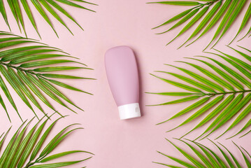Composition with empty travel cosmetics bottle palm leaf on pink background Top View