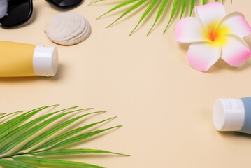 Obraz na płótnie Canvas Summer composition with sunblock lotion bottles, palm leaf, sea shells and plumeria on pink background copy space Summer vacation and skin care concept spf uv-protect cosmetics