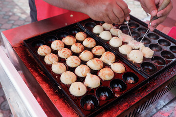 the process of cooking takoyaki in a sponge mold pan. typical Japanese street food snacks