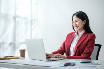 Portrait of smile beautiful business asian woman in red suit working office desk computer. Small...