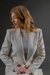 A Woman In A White Suit Is Sitting On A Stool