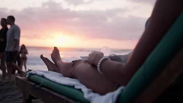 Female model lying on a beach chair and watching a beautiful orange and pink sunset at Canggu Beach
