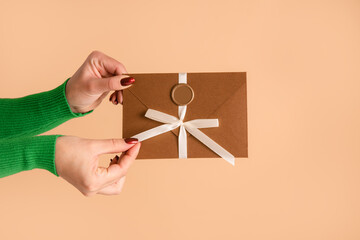 woman hand hold discount coupon or gift certificate in envelope on studio beige background