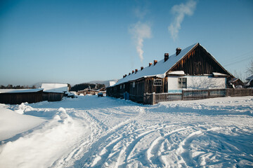 Snowy Village Winter Landscape with Traditional Wooden Houses and Smoke from Chimneys