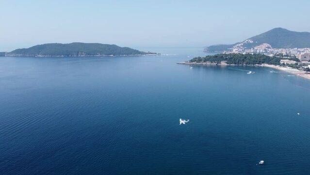 Drone view of the sea of Becici beach with mountains in the background in Rafailovici village