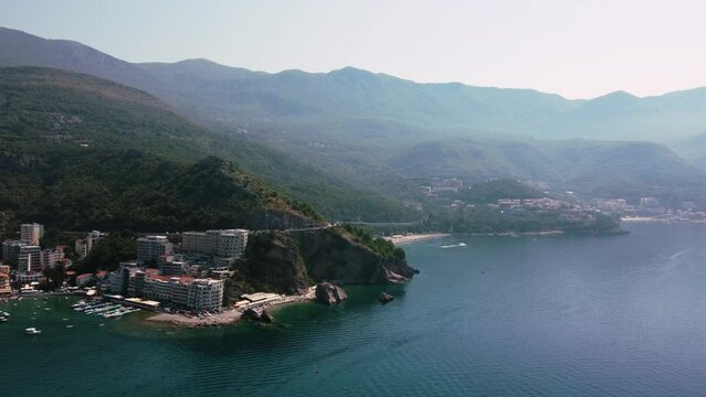 Drone view of the seaside resort of Becic beach with mountains and misty sky in Rafailovici village