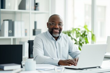 Fototapeta na wymiar A smiling, contented black businessman in a shirt is working at an office desk with a laptop