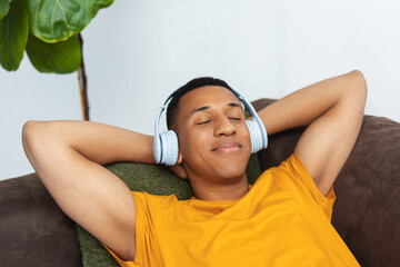 Portrait of positive overjoyed African American man wearing headphones, listening to music