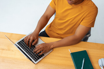Confident Latin man, programmer, copywriter typing on keyboard, using laptop sitting at workplace