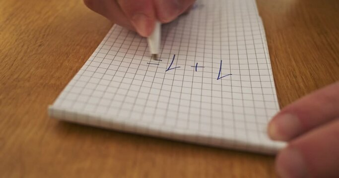 Student writes the wrong answer in mathematics simple question on sheet of paper, close-up. One plus one equals three.