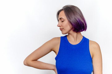 Fototapeta premium Young woman in blue sleeveless dress poses in the studio on white background. Head to the side.