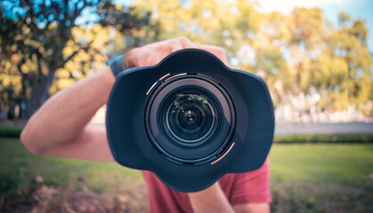 Close-up of camera lens with blurred photographer background