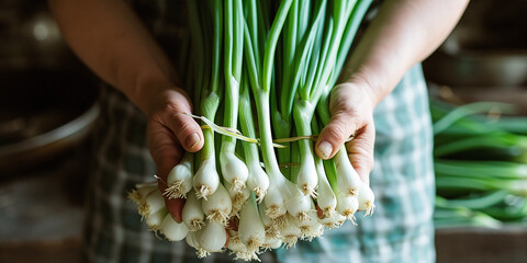 A man holds a bunch of fresh green onions.