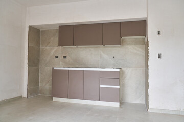Wooden cabinets with counter inside incomplete kitchen of house at construction site