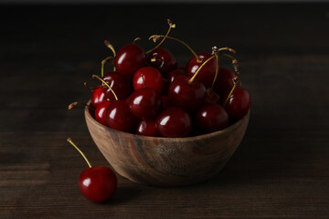 Ripe cherry fruits in a bowl on a wooden background