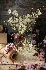 Spring twigs with flowers in a jar, on a dark wooden background.