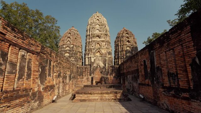 Wat Si Sawai at Sukhothai Historical Park. Three prangs (pagodas) are surrounded by a laterite wall. Inside the wall, the viharn in the west, built of laterite in the Lop Buri or Hindu-style
