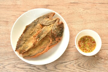 deep fried black-banded trevally fish on plate dipping spicy chili sauce  