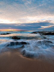 Flowing water over rocks on the beach shore.