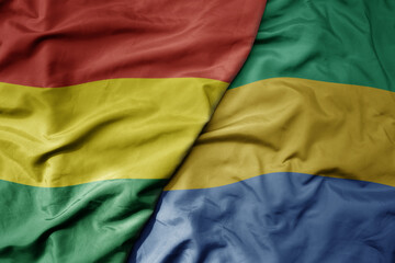 big waving national colorful flag of gabon and national flag of bolivia .