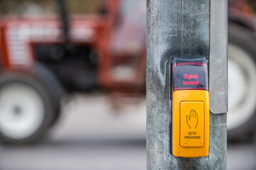 Gelber Druckschalter an Ampelanlage für Fußgänger mit Leuchtschrift Signal kommt vor...