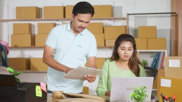 Coworkers working together at ecommerce warehouse by checking or placing order list from inventory - concept of online small business, communication and collaboration