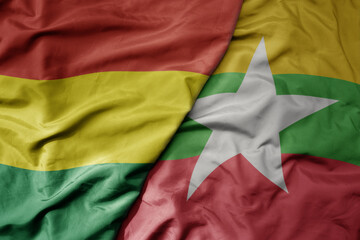 big waving national colorful flag of myanmar and national flag of bolivia .