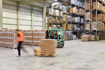 warehouse worker in a forwarding agency - interior with forklift - transport and storage of goods - 729266107