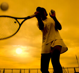 silhouette of a girl tennis player playing tennis against the background of the sunset sky