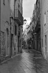 a narrow street with a lamp post and buildings - obrazy, fototapety, plakaty