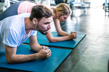 Obraz premium Sport active caucasian man and woman friend doing plank position indoor sport gym