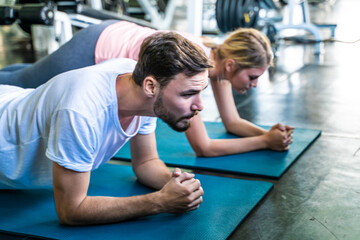 Sport active caucasian man and woman friend doing plank position indoor sport gym