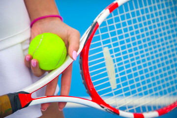 Close-up of a tennis player's hand holding a tennis ball and racket - obrazy, fototapety, plakaty